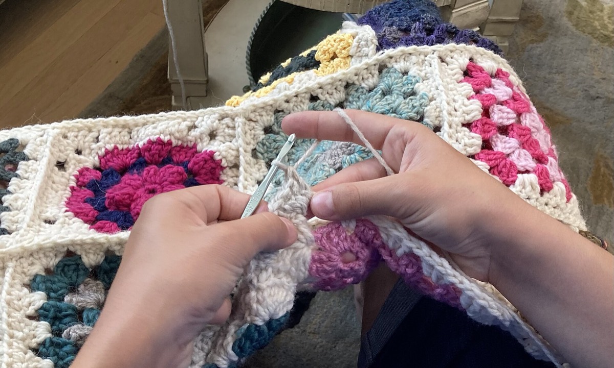 A crocheter holding a hook and maintaining tension in the yarn