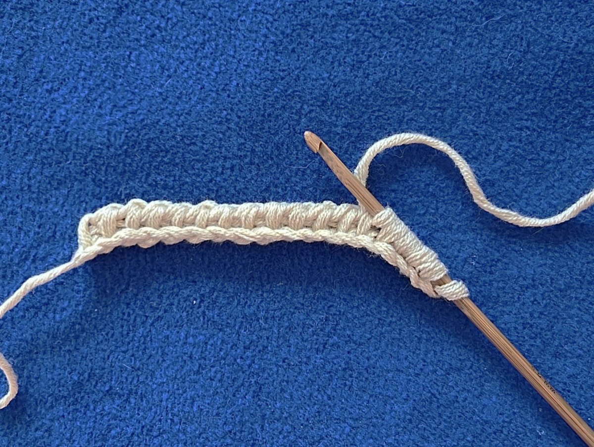The beginning of a Tunisian crochet project on a long hook